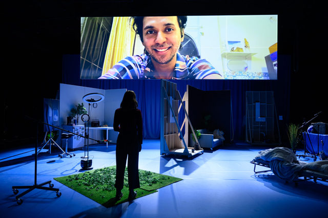 THE VILLAGE: an actor appears live on the big screen above the stage